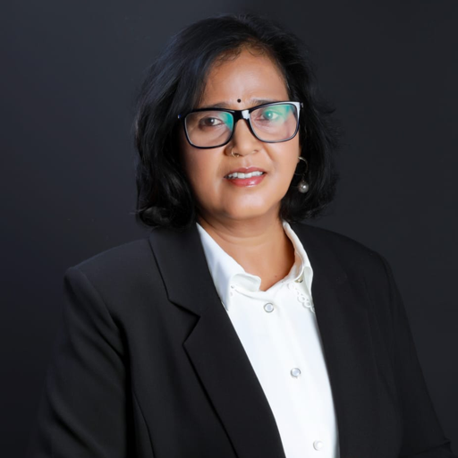 A warm and welcoming photo of the principal, Mrs. Jyoti Joshy, in his office